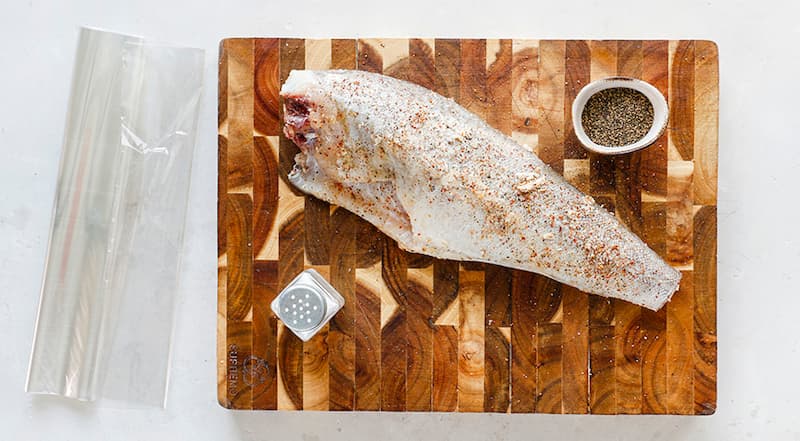 Для приготовления трески в рукаве предварительно разогрейте духовку до 190 °С в режиме «верх-низ», без конвекции. Застелите противень бумагой для выпечки (на всякий случай). Подготовьте пакет для запекания: отмотайте от рулона пленку длиной примерно 50 см