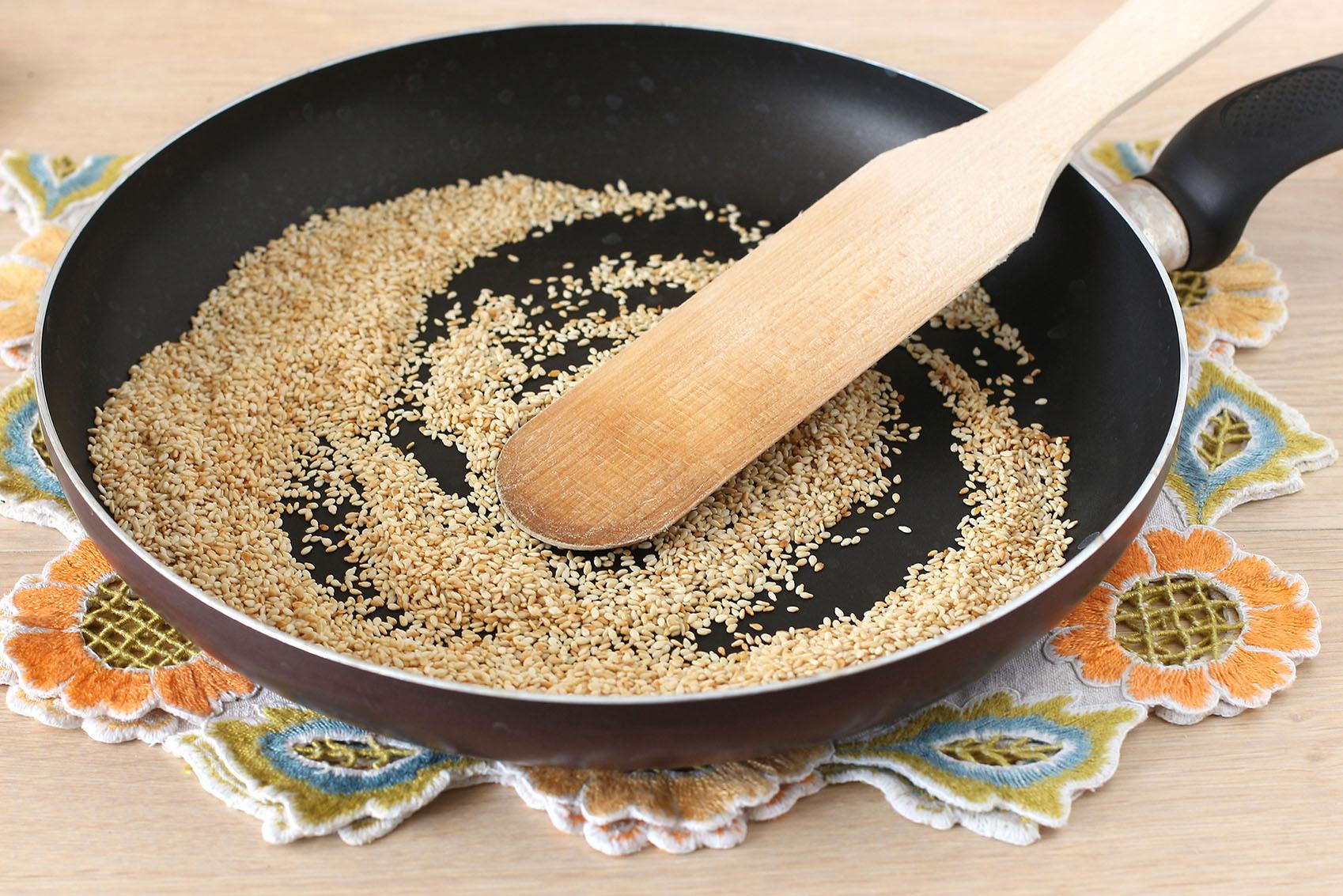 На сухую сковороду насыпьте кунжут и семена зиры. Слегка поджарьте их на маленьком огне до легкого золотистого оттенка. Важно не пережарить кунжут, иначе он может начать горчить.
