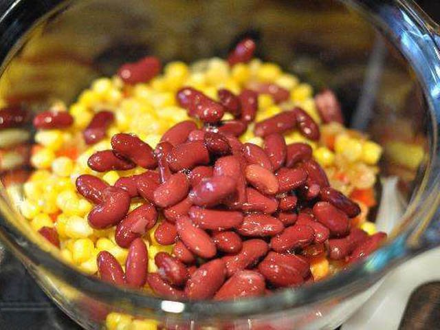 Курицу нарежьте на маленькие кубики и переложите в сковороду. Слейте с фасоли оставшийся соус, он больше не пригодится. С кукурузы тоже слейте жидкость. Добавьте в сковороду фасоль и кукурузу.