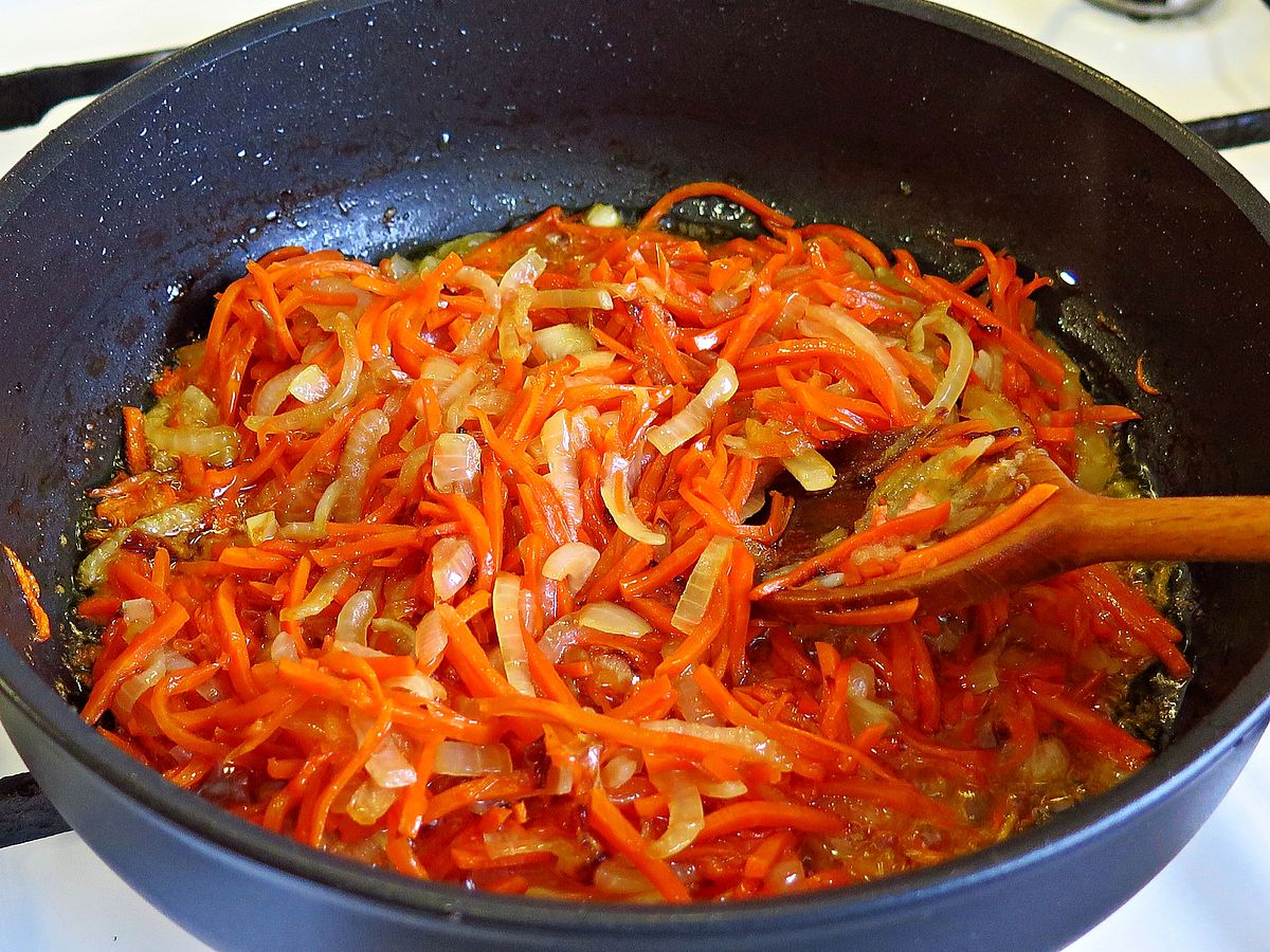 Возьмите сковороду и поставьте ее на плиту, после чего налейте в нее три-четыре столовых ложки растительного масла и выкладывайте предварительно мелко нарезанную головку репчатого лука. Возьмите крупную терку и натирайте одну морковь, после чего выложите 