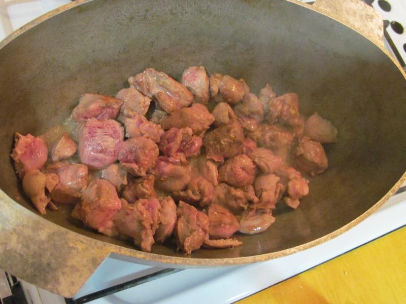 Ставим казан на сильный огонь, добавляем в него растительное и топленое масло. Нагреваем их, а после выкладываем в казан нарезанное мясо. Обжариваем мясо, помешивая, в течение 5 минут. Далее добавляем к мясу лук и продолжаем готовить их вместе, время от в