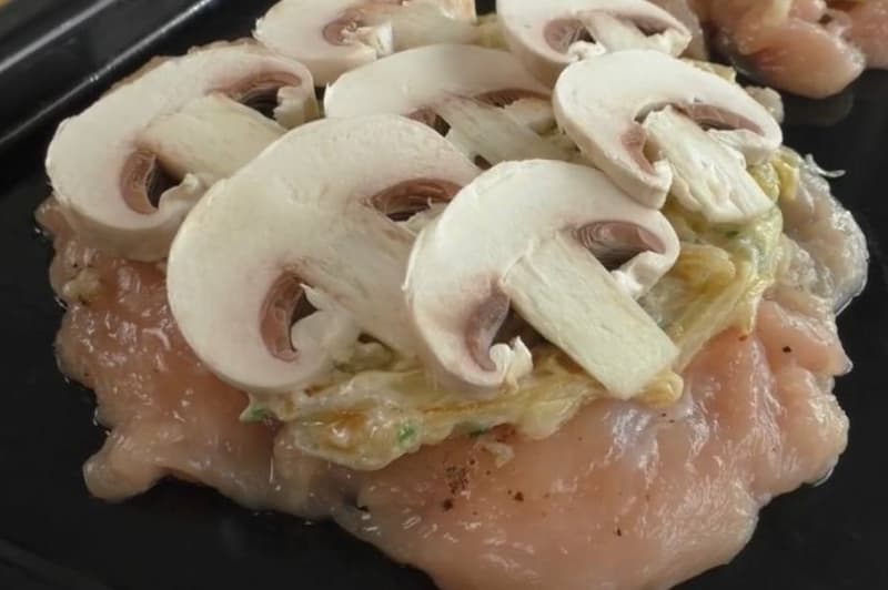 Застилаем пергаментом протвень. Раскладываем кусочки мяса. На каждый кусочек выкладываем обжаренный лук и грибы (помидор по желанию). Сверху засыпаем сыром.