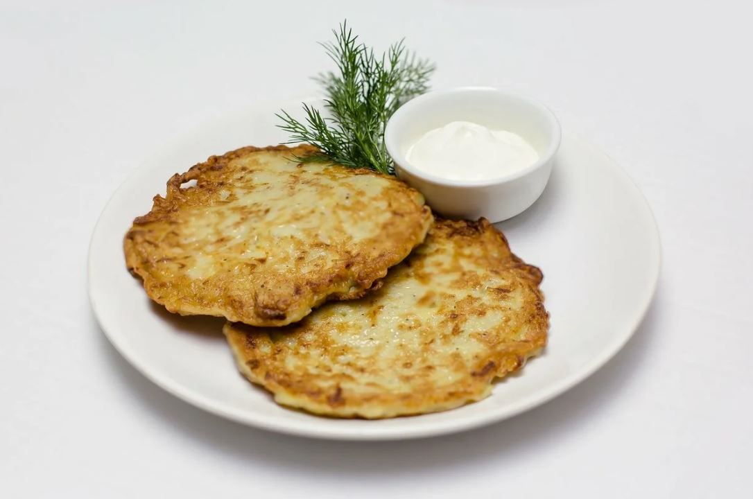 Снимаем их аккуратно деревянной лопаткой на тарелку, застеленную салфеткой, чтобы остатки растительного масла стекли. Подаем драники к столу со сметаной и свежими овощами и зеленью. Приятного аппетита!