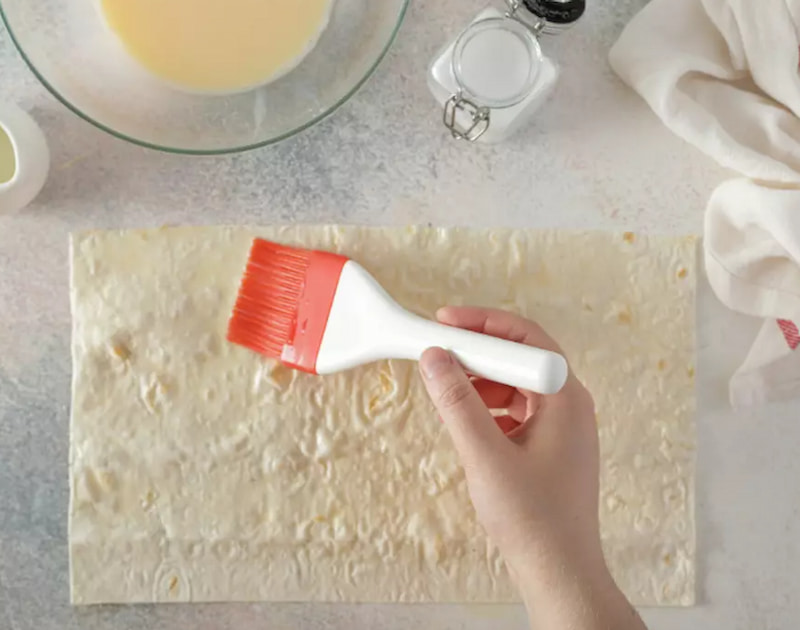 Лаваш разрежьте на одинаковые прямоугольники и обильно смажьте яичной смесью.