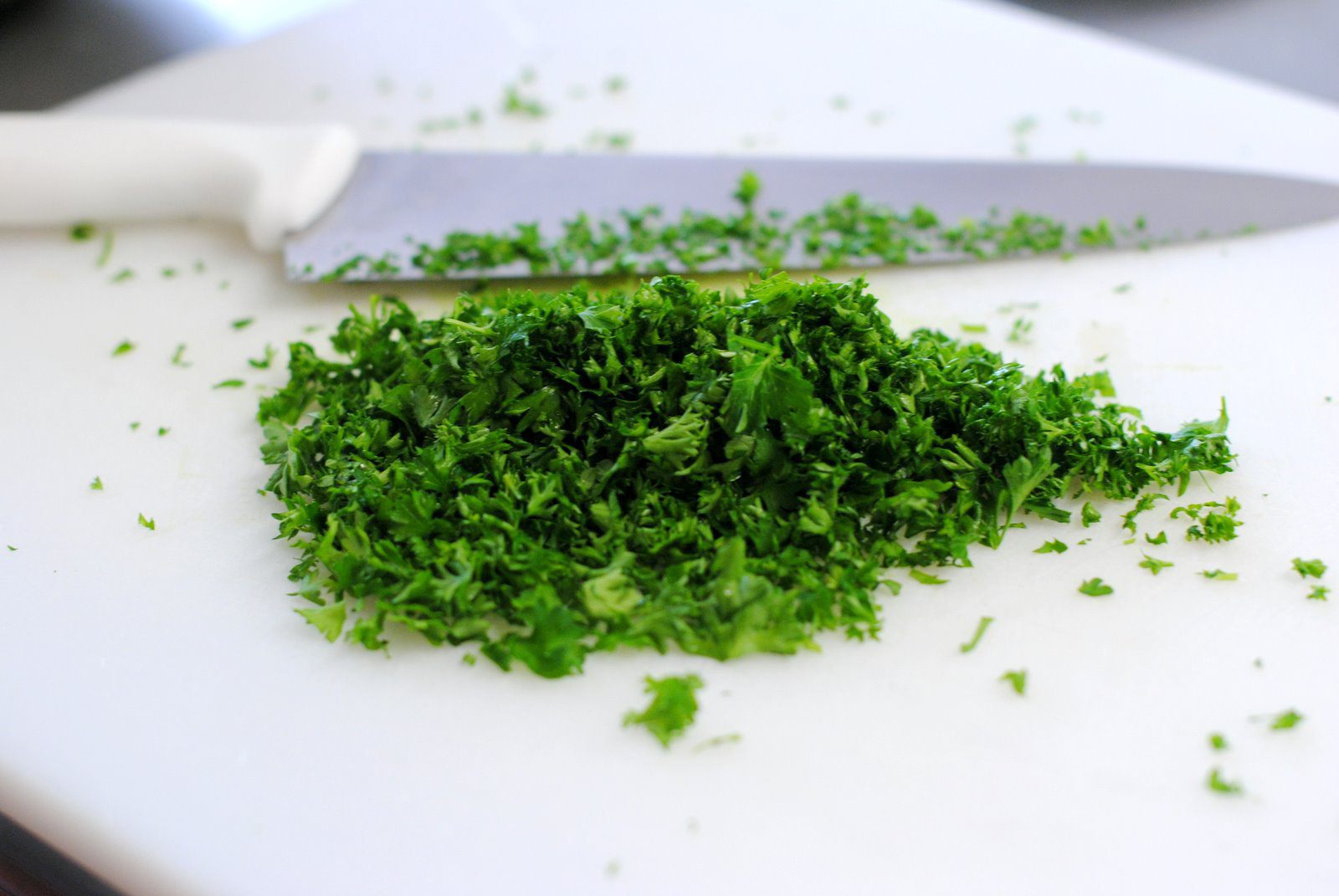 А тем временем измельчаем зелень. Это может быть укроп и петрушка или что-то одно из них. Чеснок очищаем, пропускаем через пресс. Выкладываем творог в миску. Сюда же отправляем измельченную зелень и чеснок, солим. Перемешиваем.