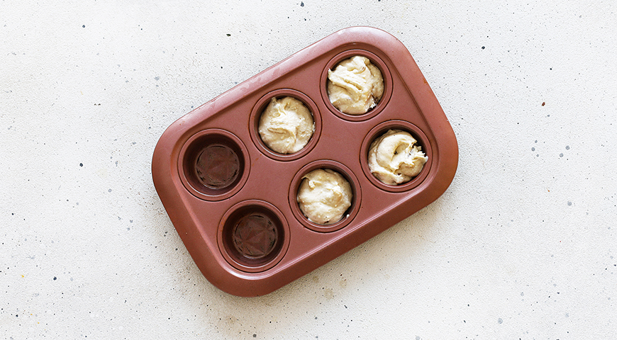 Подготовьте формочки для кексов. Идеально подойдет большая силиконовая с порционными выемками. Выложите в них тесто ложкой, стараясь наполнять не более чем на половину, потому что кексы поднимутся в процессе выпекания.