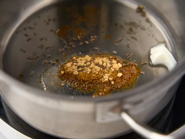 Разогрейте в кастрюле кокосовое масло. Добавьте куркуму, имбирь, кардамон и тмин. Обжаривайте специи на среднем огне 1 минуту.
