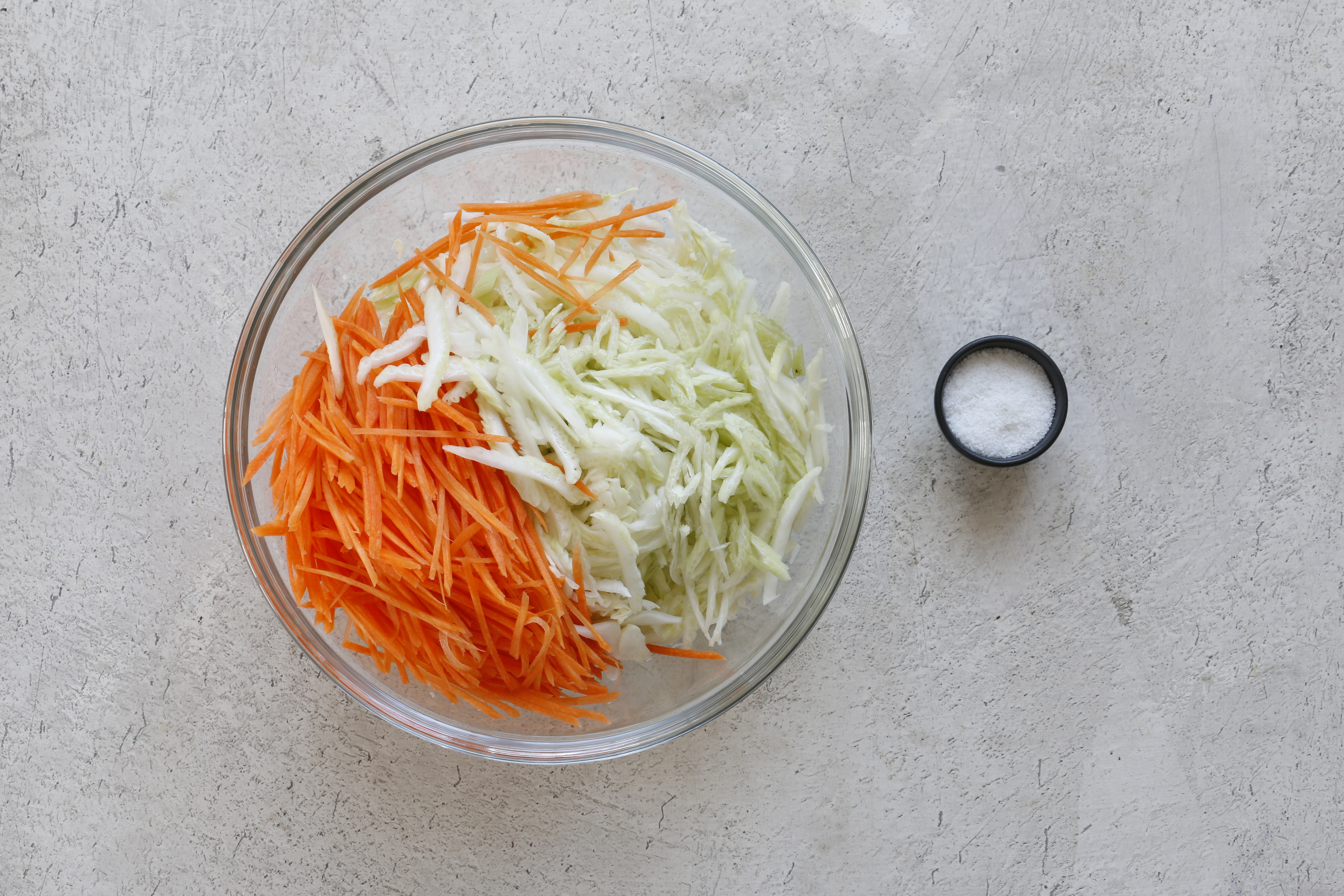 Очистите морковь и нарежьте вдоль пластинами толщиной 3 мм. Затем нарежьте по диагонали поперек тонкой соломкой. Смешайте с капустой и сельдереем, посолите, немного пожмите руками.