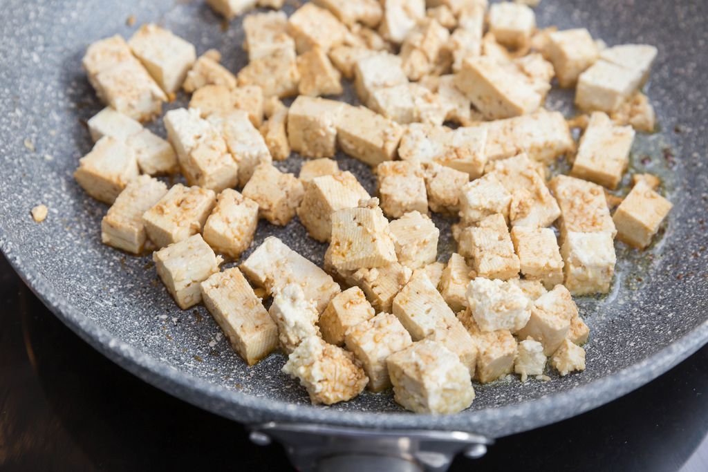 Пока варится суп, тофу нарезать небольшими кубиками. В тарелке смешать пшеничную муку и кунжут. Кубики тофу обвалять в смеси муки и кунжута. Оливковое масло разогреть на сковороде. Обжарить в нем кусочки тофу со всех сторон.