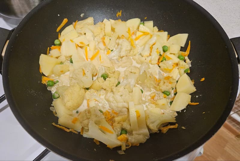 Очистите картофель, нарежьте его крупными кубиками и добавьте в сковороду. Туда же выложите горошек. Влейте кокосовое молоко. Посолите по вкусу. Накройте крышкой и тушите 15-20 минут на слабом огне.Готовое карри посыпьте кинзой, и можно подавать блюдо на