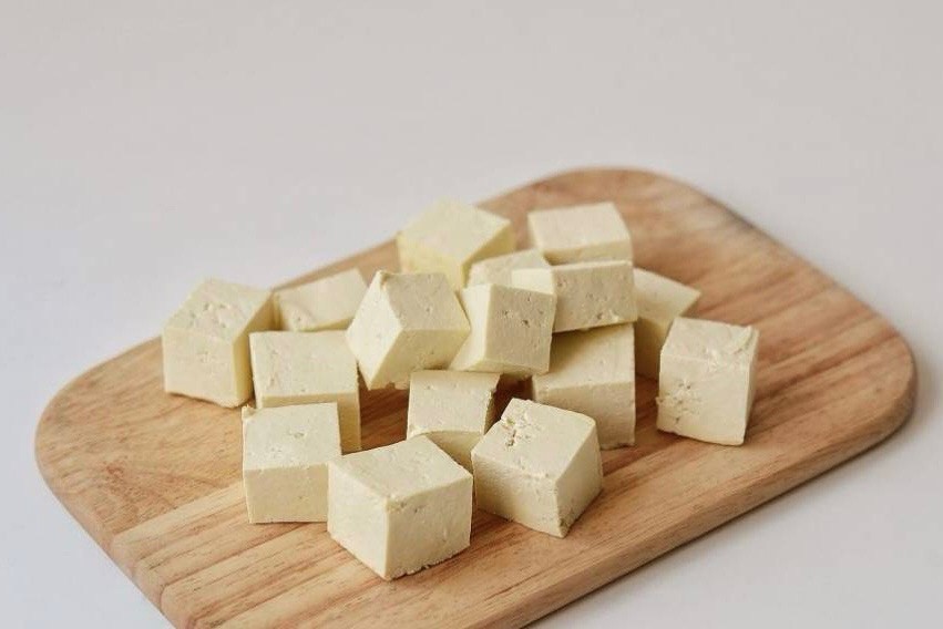 Одновременно нарежьте тофу кубиками со стороной 2 см, обваляйте в крахмале, стряхните лишнее. Обжарьте тофу в сковороде с оливковым маслом до золотистого цвета, 5–7 мин.