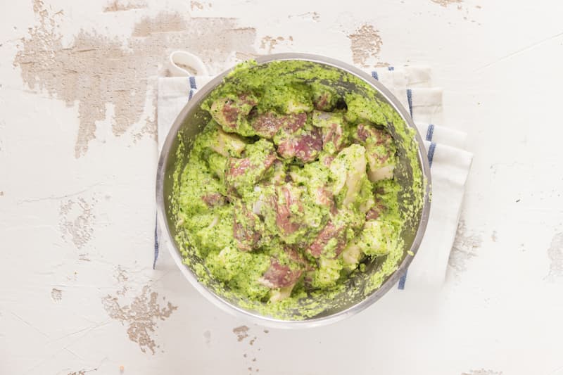 Приготовьте маринад для шашлыка. Лук очистите и нарежьте на произвольные кусочки, сложите в чашу блендера, добавьте зелень, коньяк, уксус и масло, измельчите до однородности и залейте мясо. Добавьте соль и перец, перемешайте и поставьте мясо мариноваться 