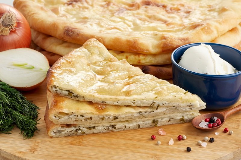 Готовое тесто делим на несколько частей. Каждую раскатываем в тонкую лепешку. В центр лепешки кладем начинку, края скрепляем как мешочек, и снова раскатываем колобок с начинкой в лепешку. Пирог кладем в смазанную маслом форму. В центре лепешки делаем небо