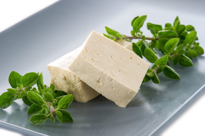 Сыр тофу разрезаем на 2 одинаковых по размеру куска. Обваливаем каждый кусок в муке. Обжариваем сыр на растительном масле со всех сторон до золотистой корочки. После чего выкладываем его на бумажное полотенце, чтобы впиталось в него лишнее масло.