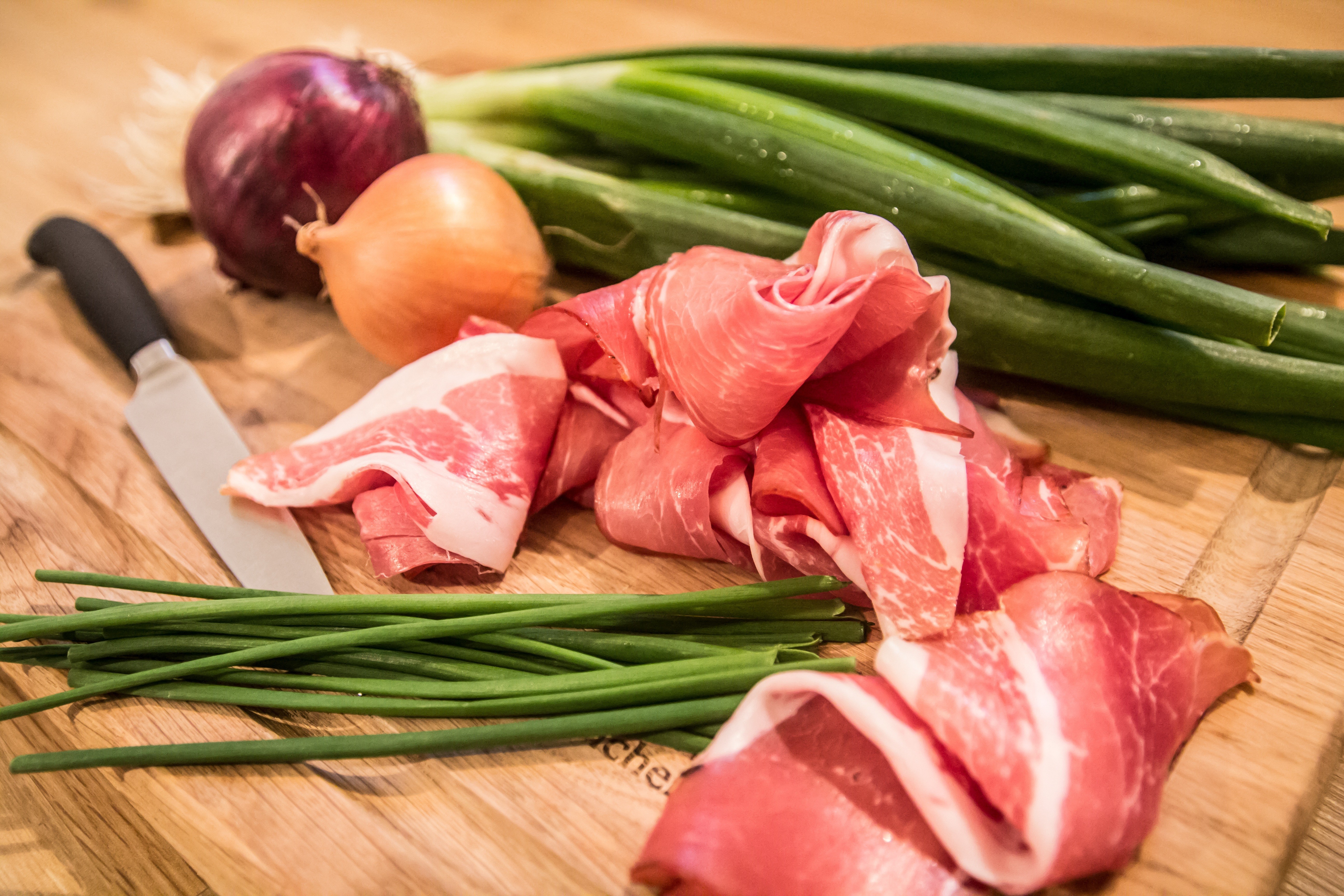 В это время приготовьте соус. Как сделать соус? Нарежьте кубиками бекон и оставшуюся луковицу. На сковороде разогрейте растительное масло, выложите в него лук и бекон. Обжаривайте их на небольшом огне до золотистого цвета. В конце приготовления добавьте п