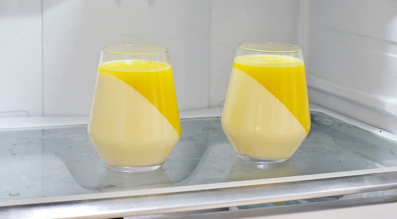 В оставшихся 100 мл апельсинового сока замочите 14 г желатина на 10 минут. Затем, помешивая, прогрейте на слабом огне, чтобы желатин растворился. Соедините с фруктовой массой. Дайте остыть и разлейте по стаканчикам с желе из ряженки. Уберите в холодильник