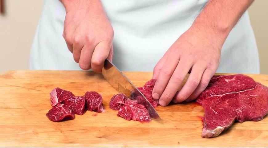 Нарежьте говядину кубиками со стороной 2,5 см. Положите мясо в миску, посолите и поперчите, посыпьте мукой и хорошо перемешайте, чтобы мука равномерно покрывала все кусочки мяса. Разогрейте большую сковороду с оливковым маслом и обжарьте мясо до румяной к