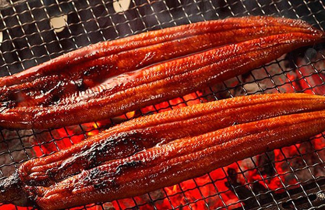 Выложите угря на решётку на некотором расстоянии друг от друга, чтобы дым равномерно обволакивал каждую тушку. В брюшко рыбы можно сделать распорки, я этого не делала так как угорь у меня был небольшого размера. Накройте аппарат крышкой и коптите в течени