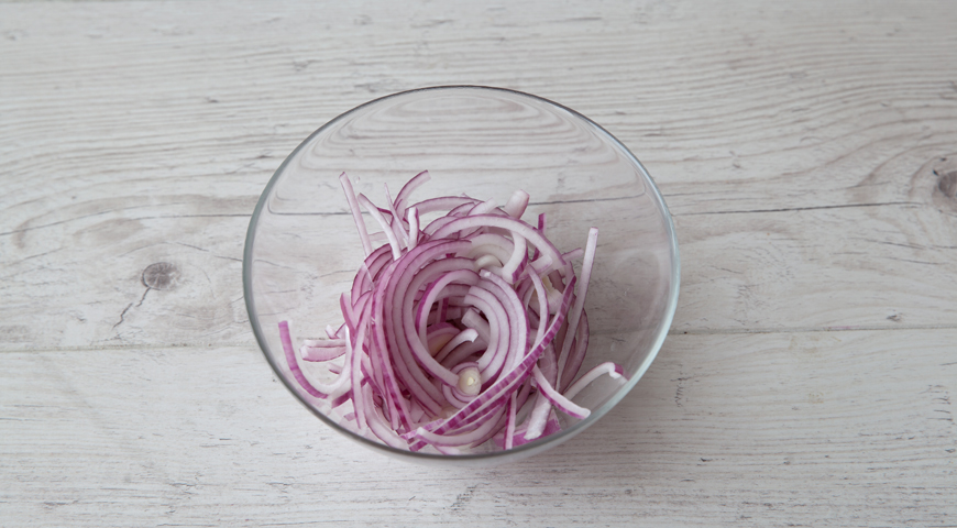 Подготовьте красный лук для греческого салата с брынзой. Очистите луковицу, разрежьте пополам и нарежьте очень тонкими полукольцами. Сложите в небольшую мисочку.