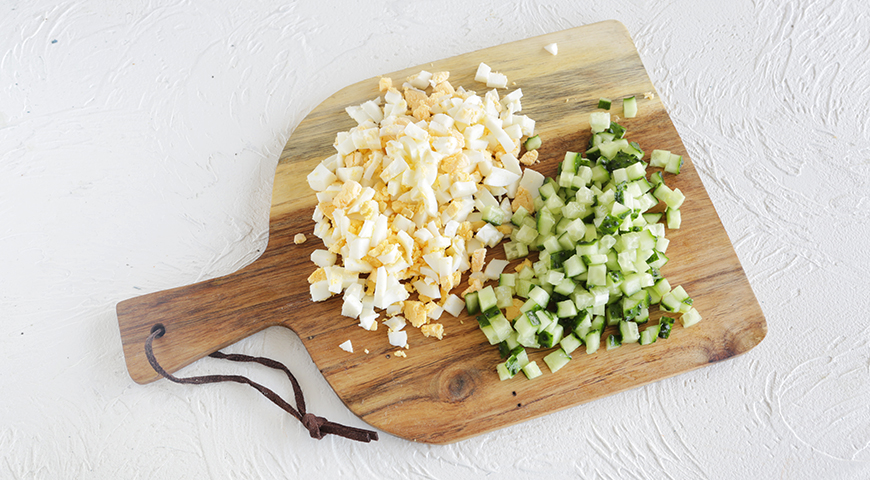 Яйца для окрошки сварите вкрутую (10 минут). Охладите проточной водой, затем очистите и нарежьте кубиками. Свежие огурцы вымойте, обсушите и нарежьте кубиками.