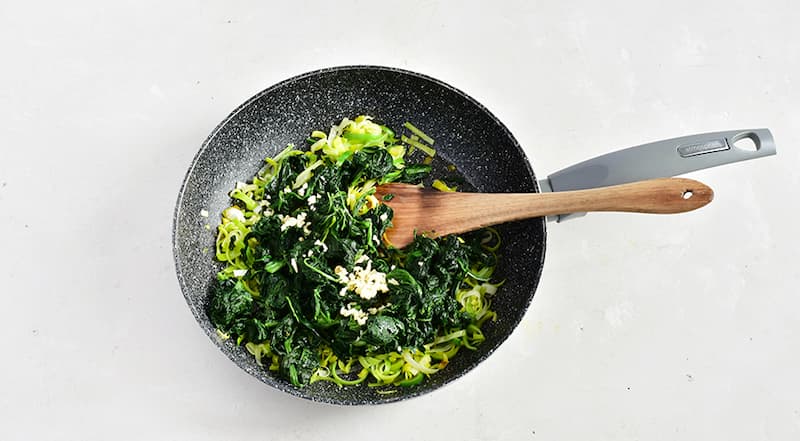 Чеснок раздавите, очистите и мелко порубите. Добавьте к порею вместе со шпинатом, тщательно перемешайте. Увеличьте огонь до среднего, прогревайте, помешивая, 2–3 мин.