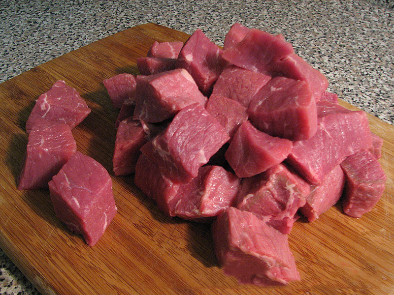 Пока жарится лук, нарезаем мякоть говядины средним кубиком. Добавляем мясо к луку. Жарим до изменения цвета мяса.