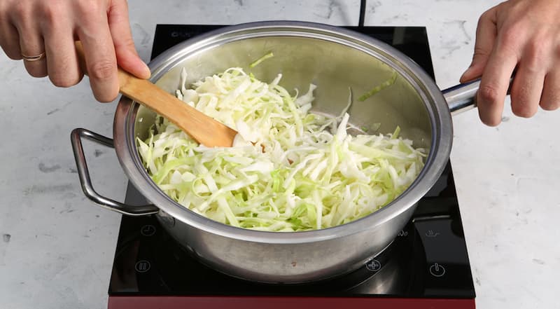 В большой сковороде нагрейте 1 ст. л. растительного масла. Выложите в нее капусту и, помешивая, жарьте 5–7 минут. Влейте оставшуюся воду и тушите на слабом огне около 8 минут. Переложите в миску.