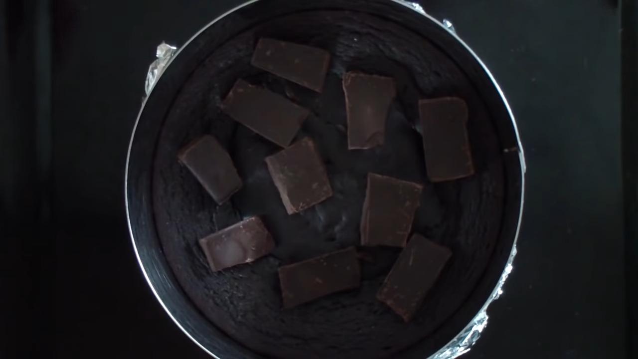 Достать готовый и еще горячий пирог из духовки и разложить по нему кусочки горького шоколада. Оставить на 2–3 минуты, чтобы шоколад растаял. После распределить лопаткой шоколадную массу по всей поверхности брауни. Также можно растопить шоколад в сотейнике