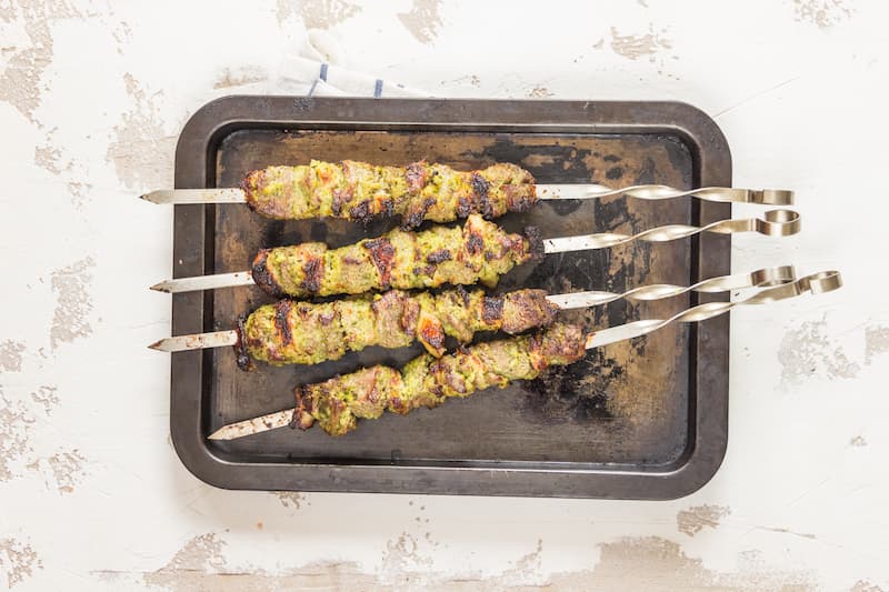 Нанижите баранину на шампуры и жарьте шашлык на углях до готовности, примерно 15–20 минут – если проколоть мясо, вытекающий сок должен быть прозрачным. Подавайте шашлык с зеленью, луком и лавашом.