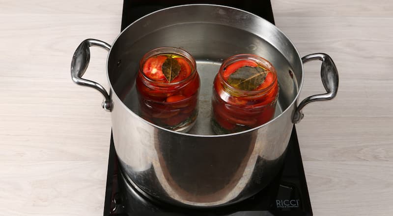 Распределите помидоры по банкам с овощами и специями. Залейте остывшим маринадом и прикройте крышками. Поставьте банки в широкую кастрюлю с горячей водой (вода должна доходить до «плечиков») и стерилизуйте 10 минут.