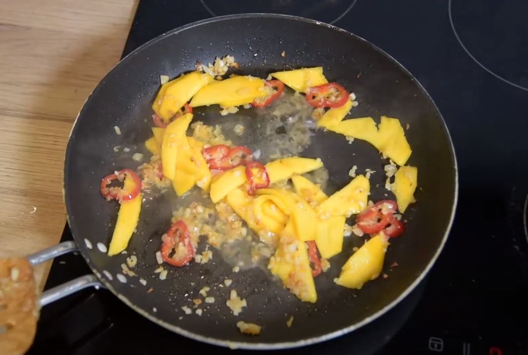 Разогреть сковородку, растопить оливковое и сливочное масло. 2-3 минуты пассировать лук, добавить слайсы манго, кольца чили и томить еще пару минут. Добавить пюре имбиря и чеснока, карри и 50-70 мл воды, томить 2-3 минуты, непрерывно помешивая. 