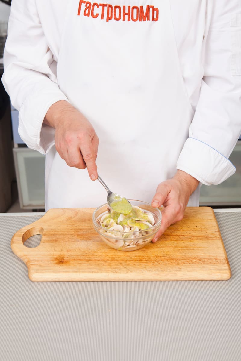 Очистите и порубите лук-шалот, мелко нарежьте листья эстрагона. В миске смешайте лук-шалот, уксус, соль и эстрагон. Влейте в заправку оливковое масло и масло грецкого ореха и взбейте до получения эмульсии. Нарежьте шампиньоны тонкими ломтиками. Отлейте по