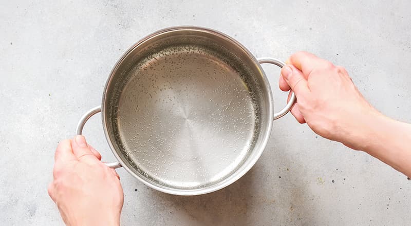 Для компота из ассорти замороженных ягод поставьте кастрюлю с водой на огонь и доведите до закипания.