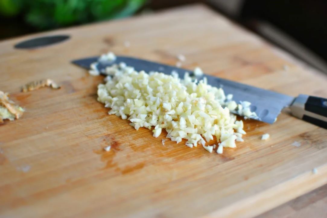 Произвольно измельчить чеснок. Добавить чеснок к зелени.