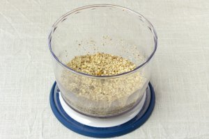 Измельчаем грецкие орехи. Лучше использовать терку: блендер размалывает их очень мелко, от этого теряется пикантность.