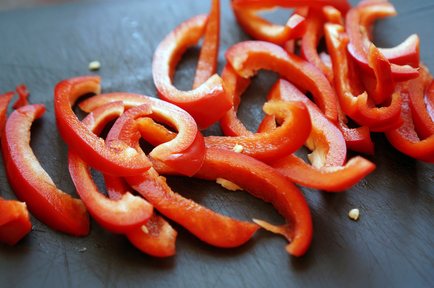 Перец вымойте и встряхните от лишней влаги. Репчатый лук очистите от шелухи. Оба овоща нужно нашинковать очень тонкими кольцами. Буквально от 2 до 3 мм. Так как пицца будет запекаться рекордно малое время, овощи должны быть максимально тонкими, чтобы успе