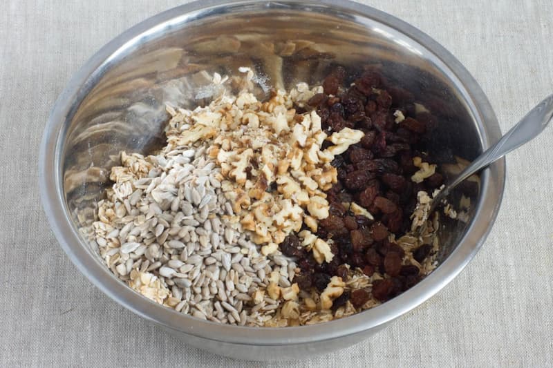 К полученной массе добавляем изюм, орехи и семена. Перемешиваем. Можно использовать разные добавки из сухофруктов, орехов и семян.