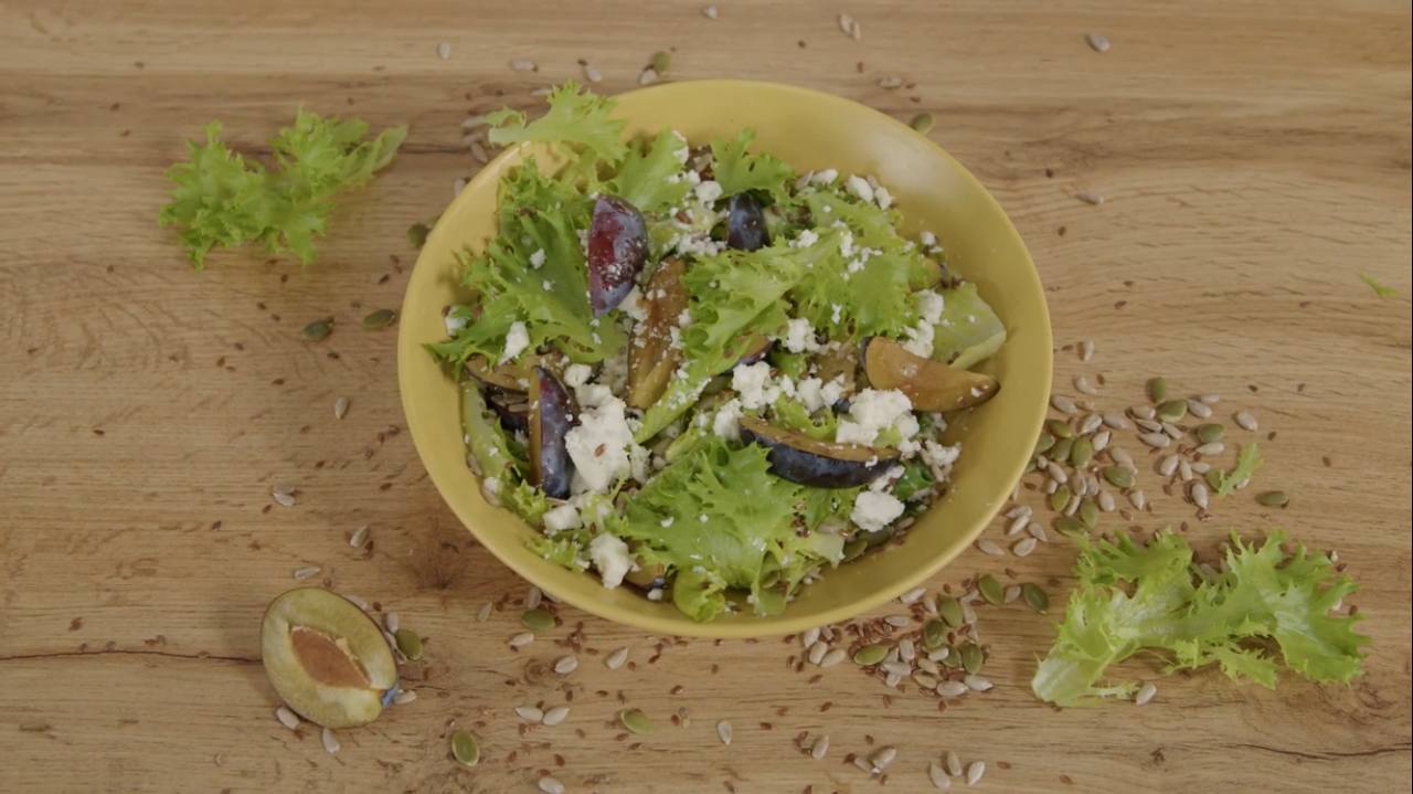 Заправляем салатные листья со сливой соусом. Ломаем хаотично кусочки брынзы, добавляем в салат и посыпаем его смесью семечек.