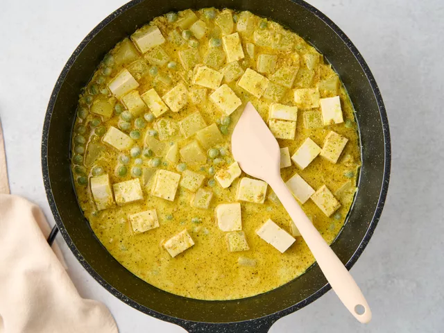 Положите в сковороду отварной картофель, кубики тофу и замороженный горошек. Влейте оставшиеся 0,5 стакана кокосового молока и 0,5 стакана воды, все перемешайте.