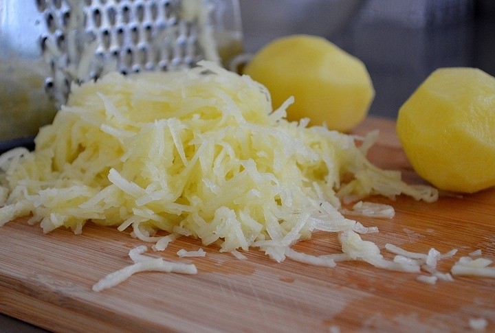 Когда картофель в мундире будет почти готов, начните натирать оставшийся сырой картофель на мелкой терке, как на драники.