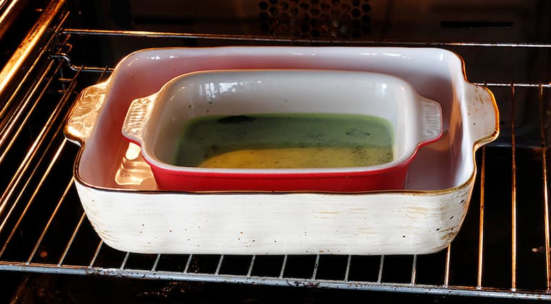 Сбрызните небольшую форму для запекания водой из пульверизатора, выложите яичную массу. Поставьте форму в глубокий противень или большую форму, налейте горячую воду так, чтобы формочка была погружена на 2/3. Поставьте всю конструкцию в духовку, запекайте 